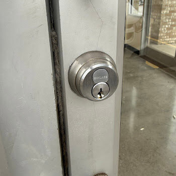 Chrome deadbolt on glass storefront door by Defense Locksmith Buffalo NY