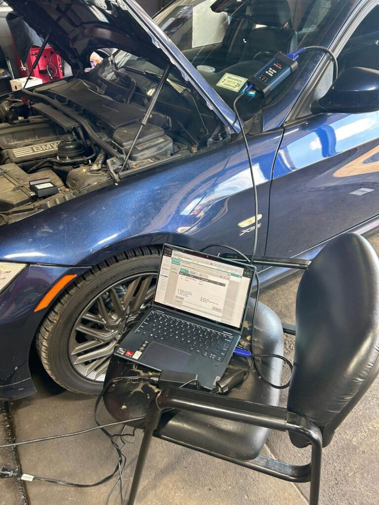 Key programming tool and laptop connected to a BMW during car computer programming in Buffalo, NY