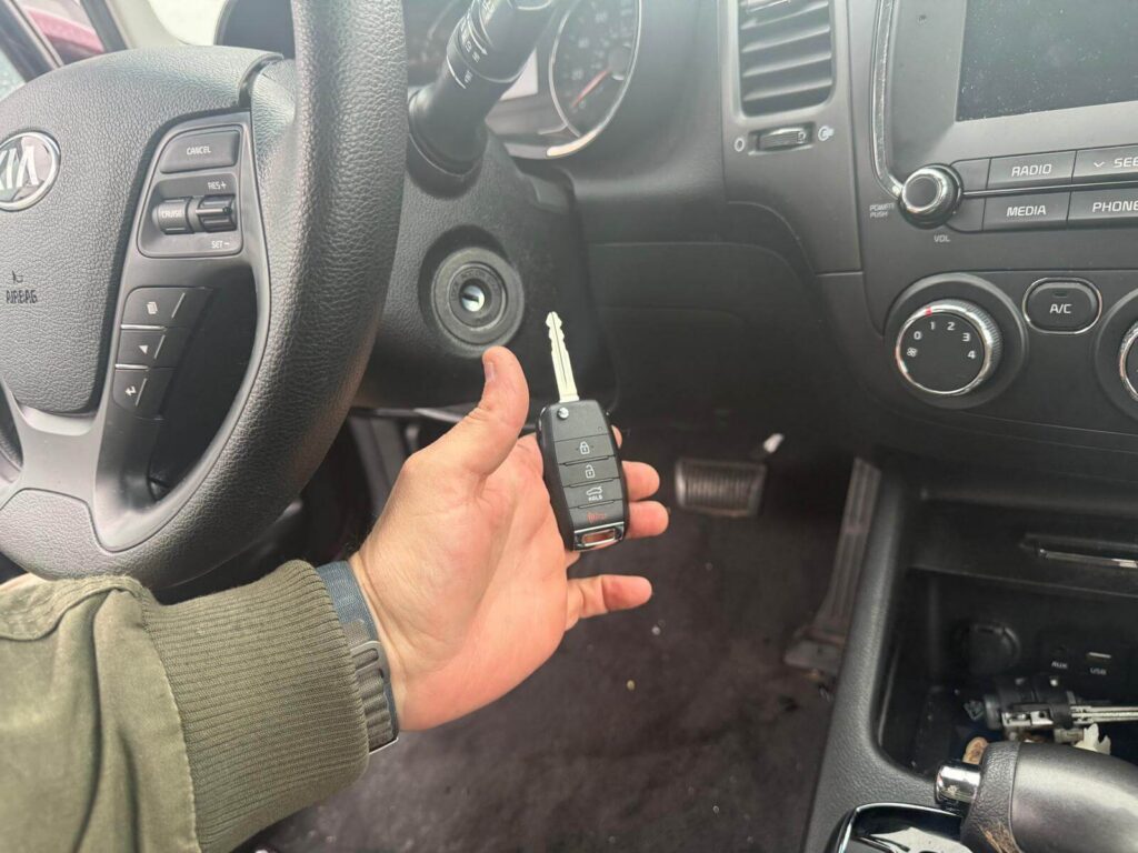 Kia car key replacement with new key fob inside the vehicle in the Buffalo Metro area