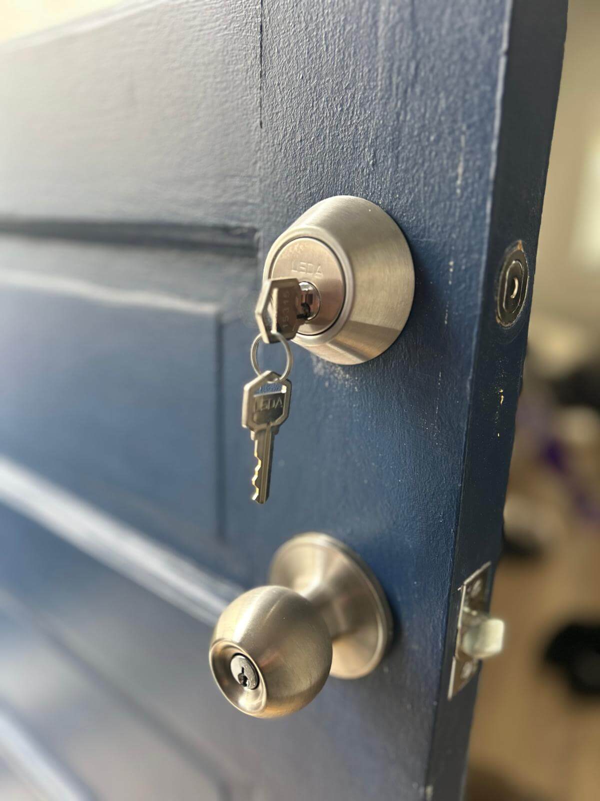Entry door deadbolt and knob on a Buffalo, NY home Deadbolt and knob lock on a blue entry door with the key in the cylinder