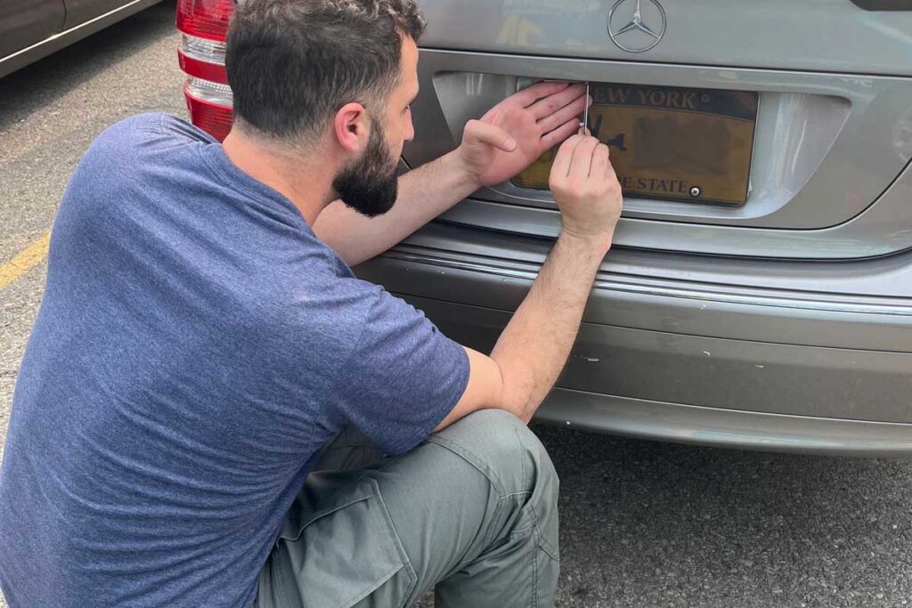 Locksmith accessing the trunk lock on a Mercedes with New York plates