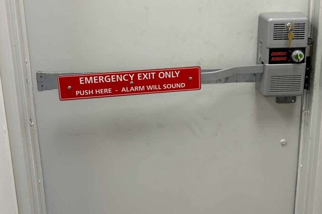 Red emergency exit panic bar push device on a commercial door