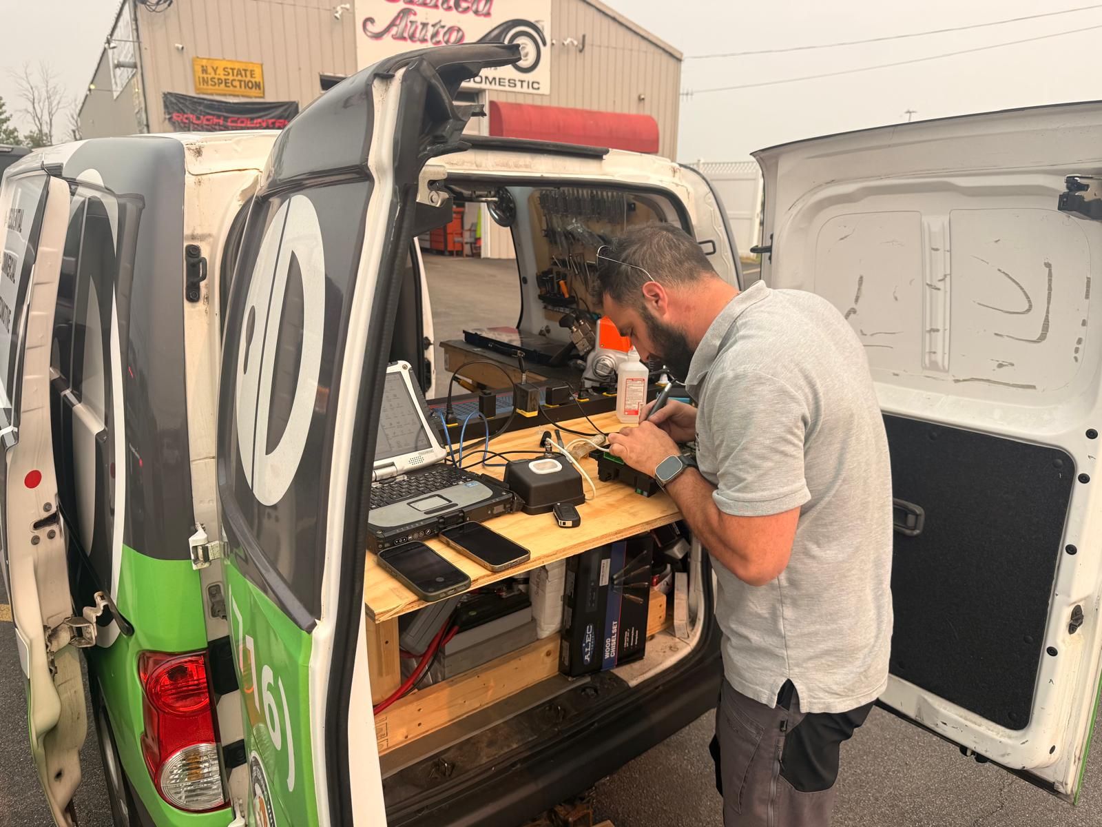 Automotive locksmith van workshop bench in Buffalo, NY Locksmith technician working at a bench inside a mobile locksmith van with a rugged laptop and key programming tools