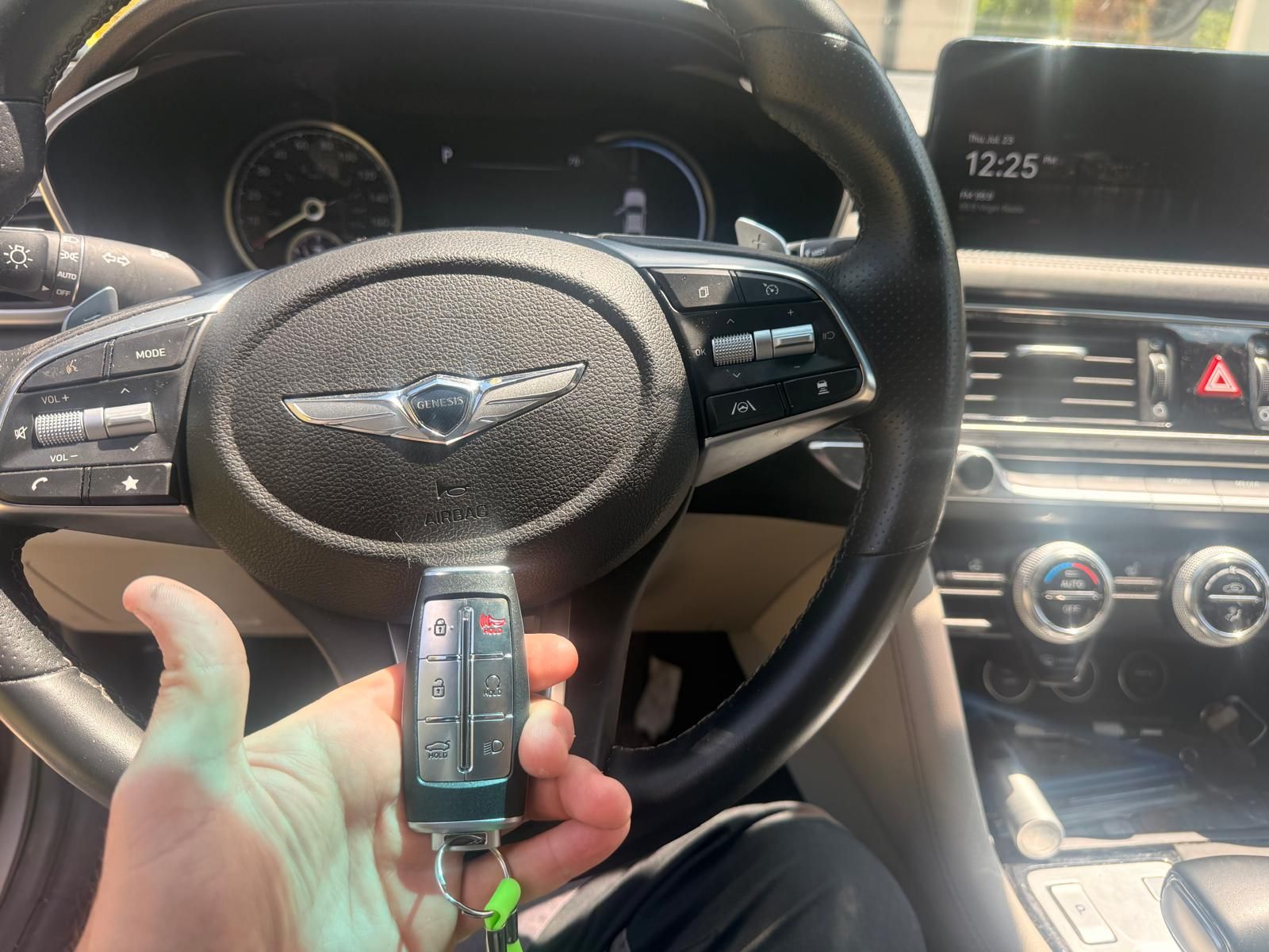 2023 Genesis G70 smart key fob replacement in Buffalo, NY Freshly programmed 2023 Genesis G70 smart key fob held at the steering wheel with the Genesis badge visible