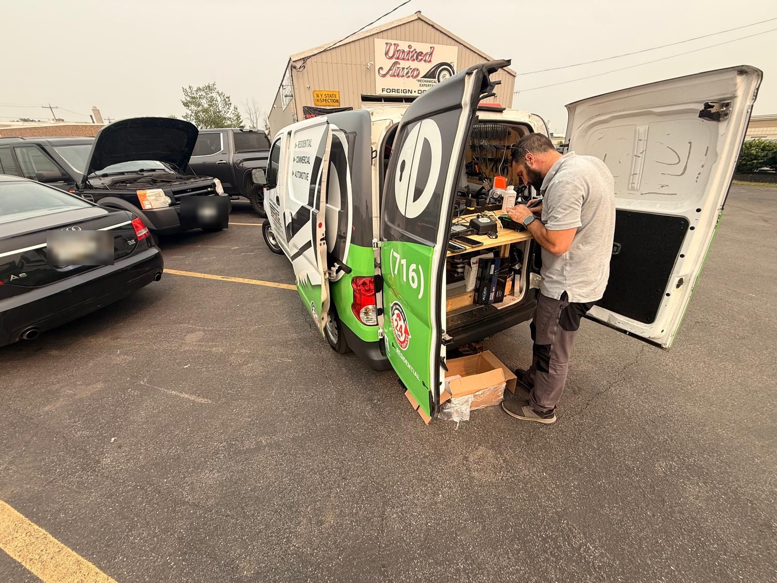 Mobile locksmith van on-site for a Land Rover key job in Buffalo, NY Defense Locksmith mobile van with rear doors open at a Buffalo auto shop, working a Land Rover key programming job