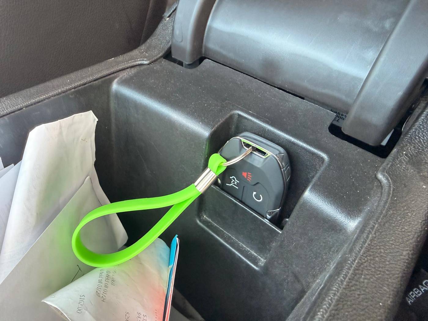 GMC Acadia key fob programmed on-site in Buffalo, NY Newly programmed GMC Acadia key fob with a green Defense Locksmith tag resting in the centre console