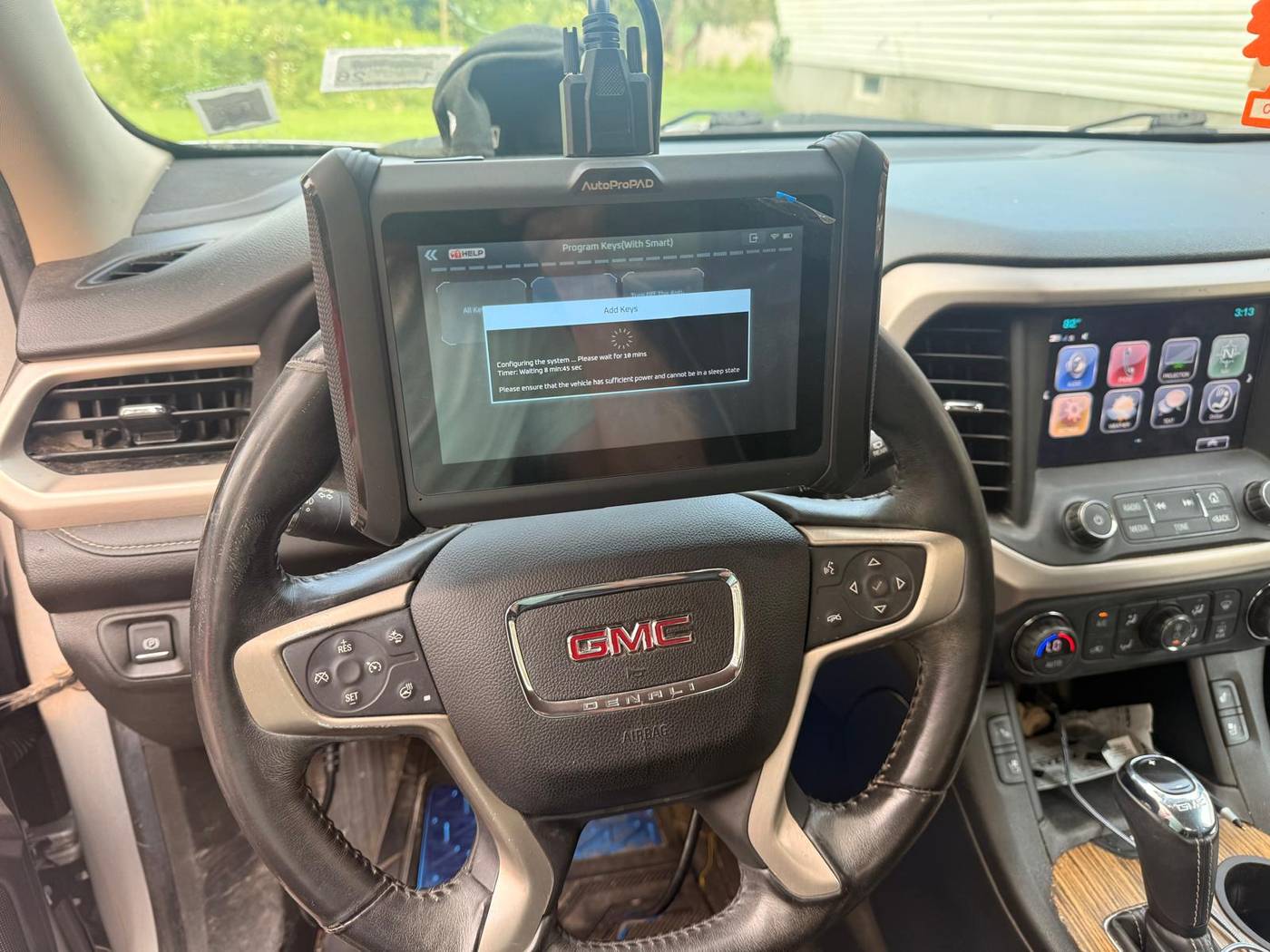 GMC Acadia key programming in Buffalo, NY Programming tablet mounted on a 2017 GMC Acadia steering wheel during on-site key programming in Buffalo, NY
